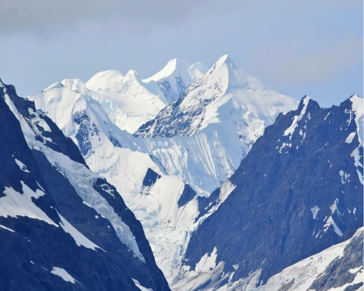 large mountains covered in snow against a cloudy sky