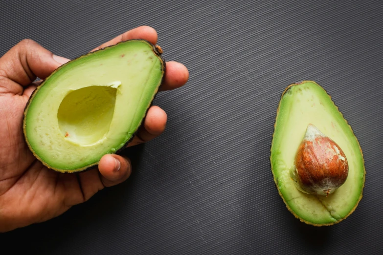 two halves of an avocado one with a seed