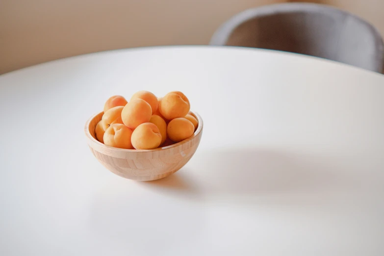 a bowl filled with oranges sitting on top of a white table