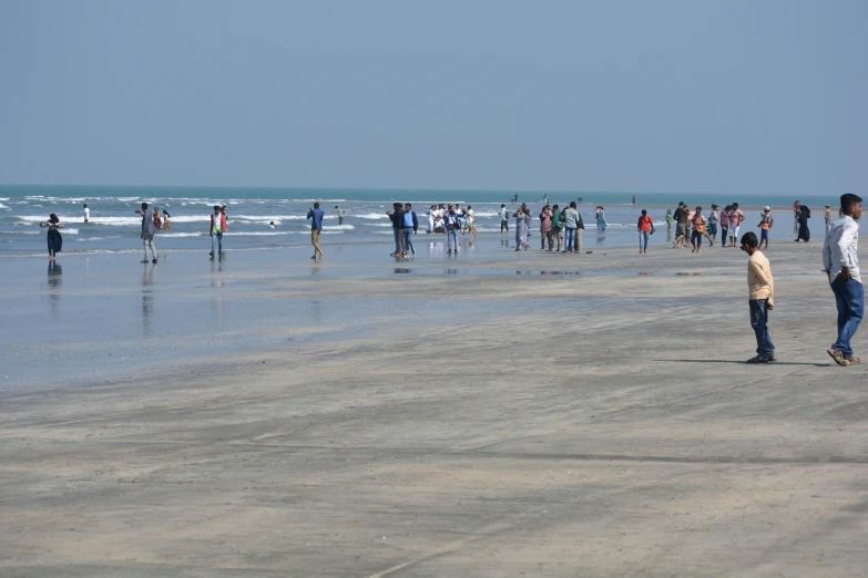 the large group of people are walking along the water