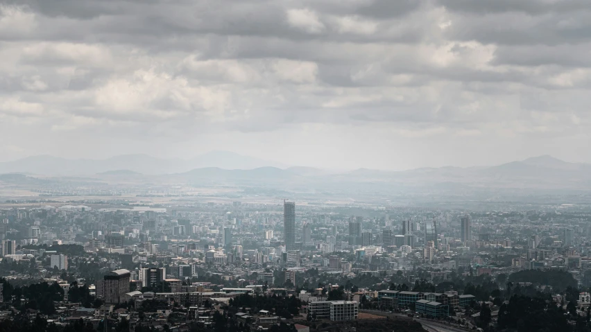 a cloudy city skyline with mountains in the distance