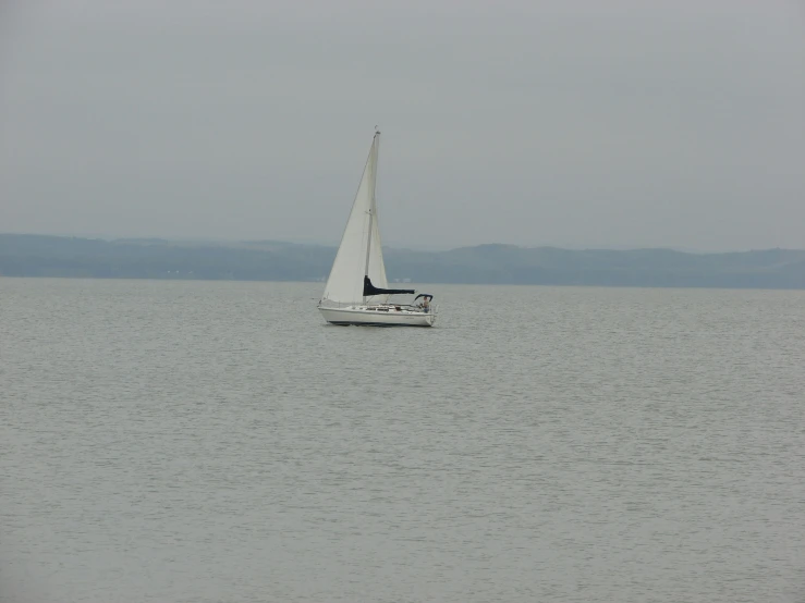 a sailboat with a black top sailing across a large body of water