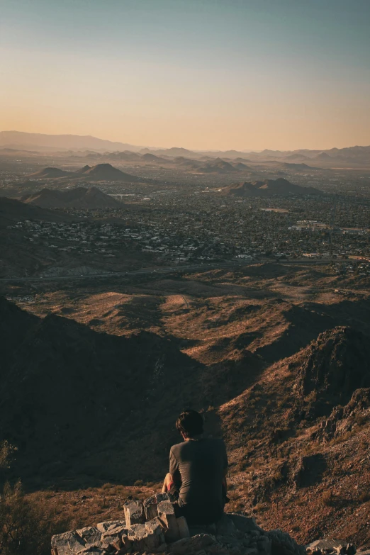 person sitting on rock in mountainous area during sunset