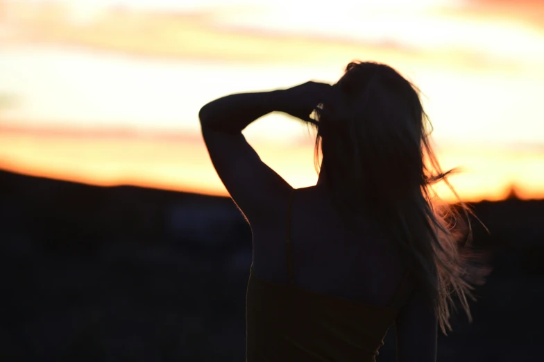 a beautiful young lady wearing a yellow bathing suit is holding her hair back