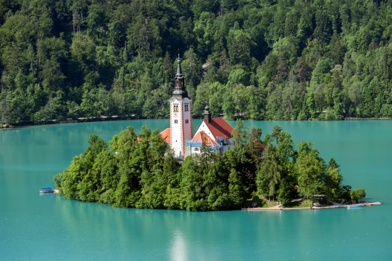 an island is surrounded by trees and a small tower with a red roof on top