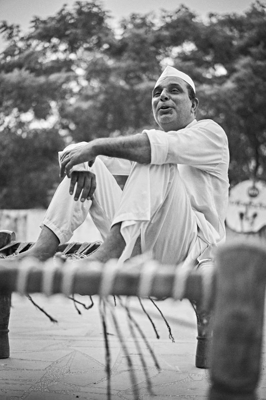 an older man in white sitting outside of a fence