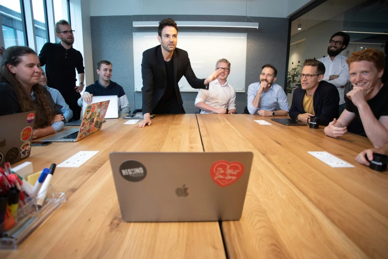 a group of people at a wooden table with an open laptop