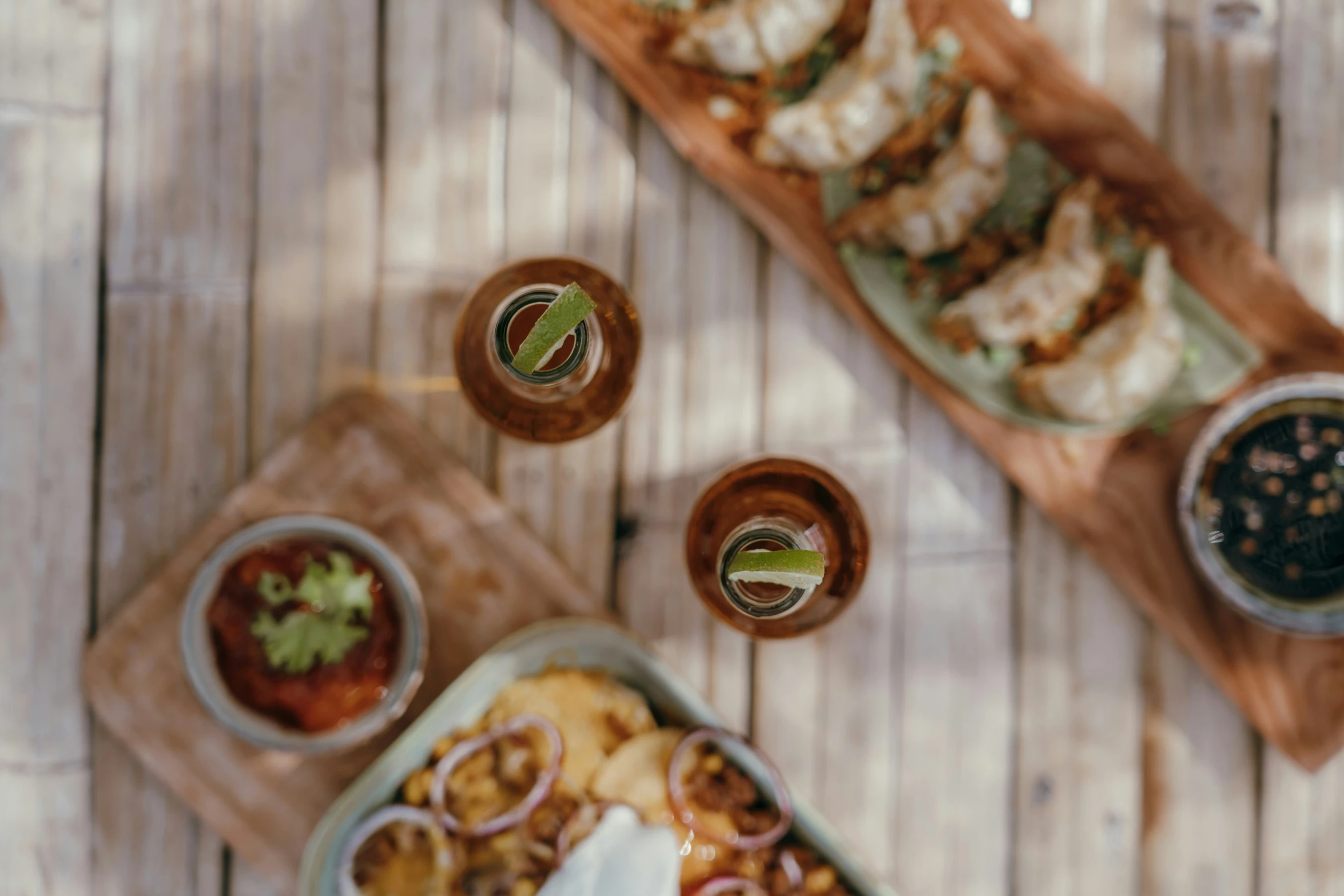 plates of food sit on a wooden table with two glasses