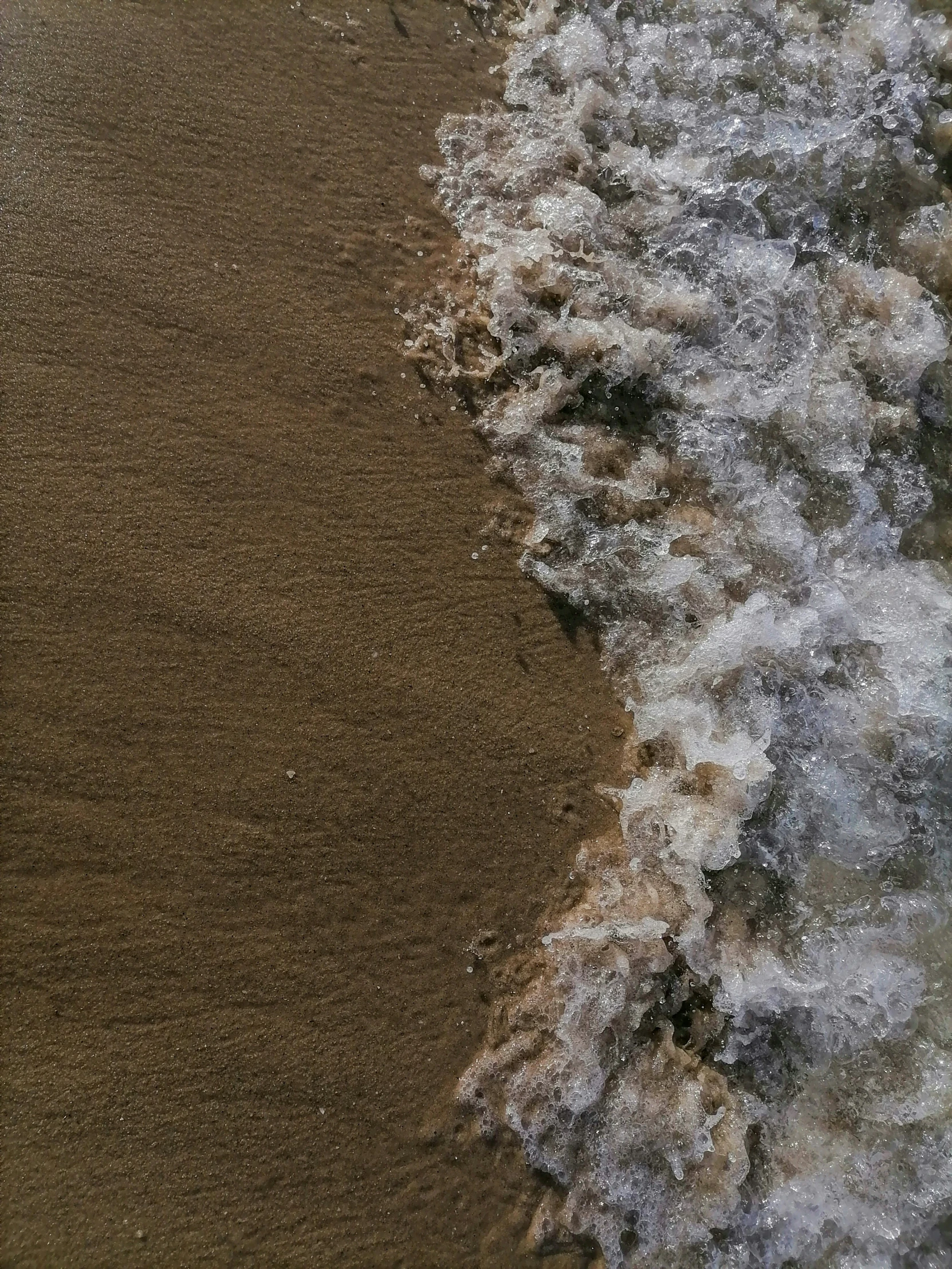 a brown and white beach area with waves coming in
