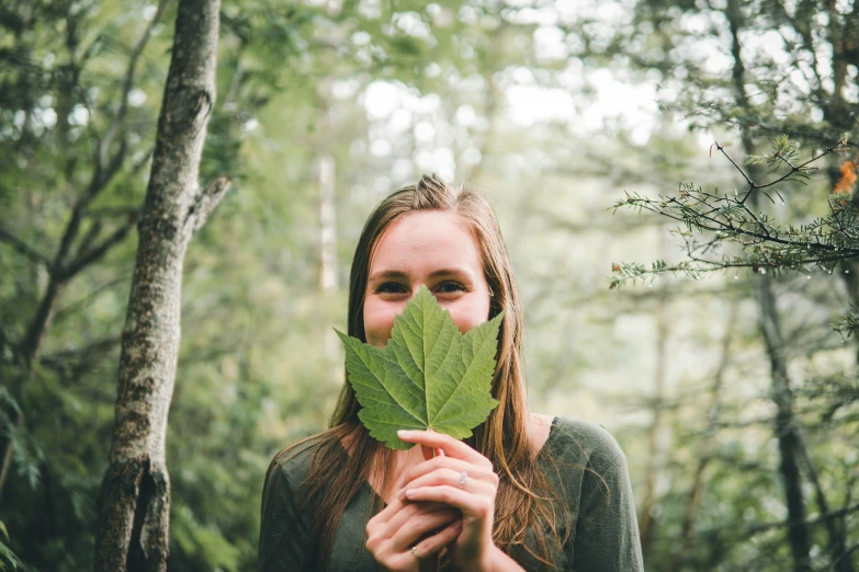 a woman covering her face with a leaf