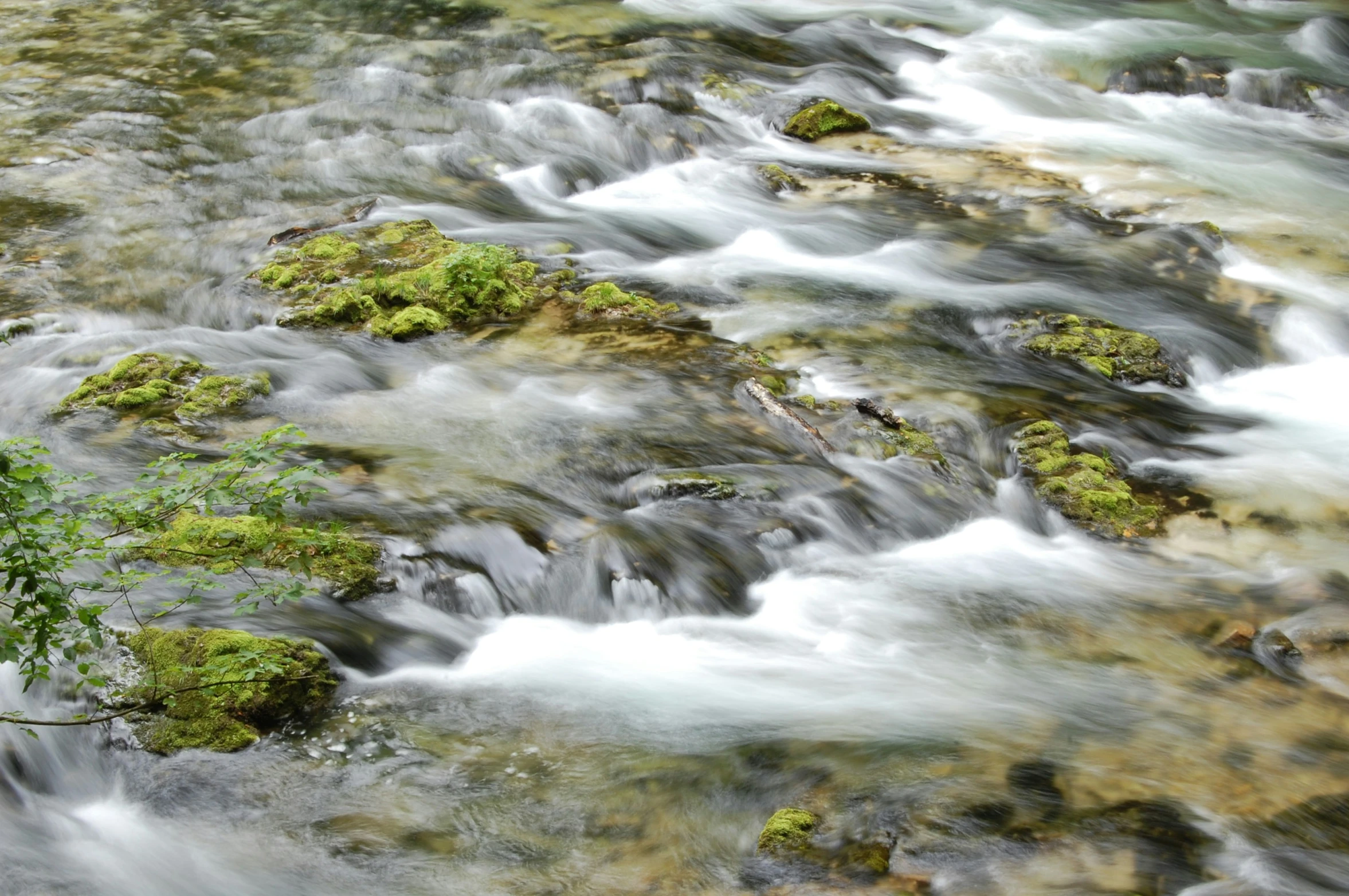 a stream of water near some green rocks