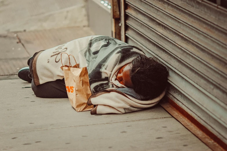 a homeless person sleeping on the sidewalk while eating soing