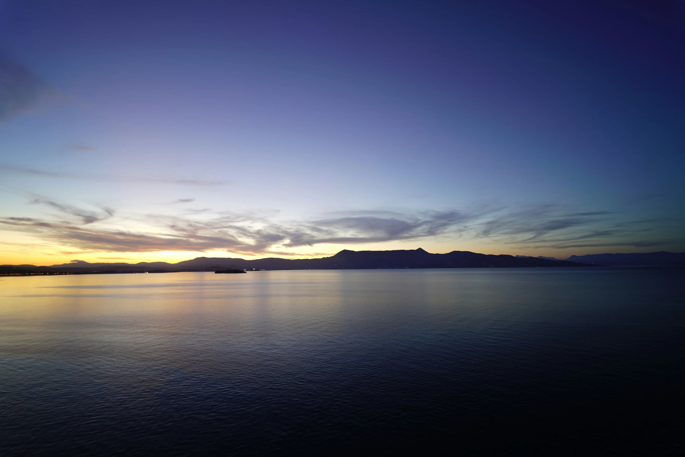 a blue sky over the ocean at sunrise