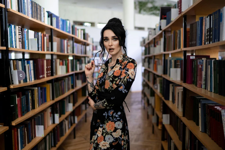 a woman standing in front of some bookshelves and holding a glass