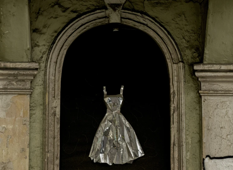 a silver dress hangs from the side of a building