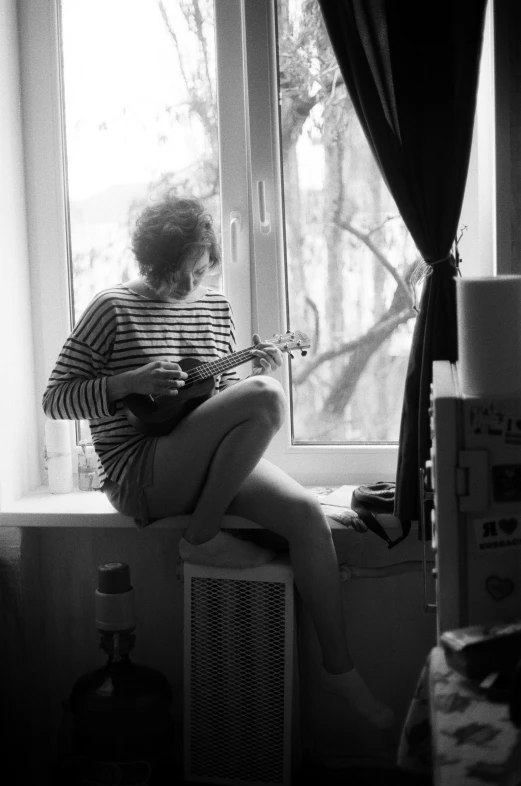 black and white po of a woman sitting on the window sill with a guitar