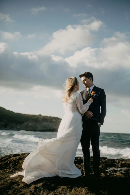 a bride and groom are at the edge of the ocean