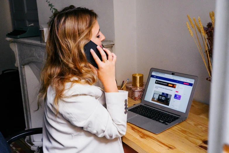 a woman talking on the phone while using her laptop