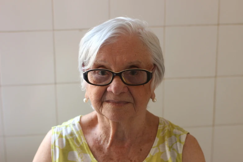 an older woman with glasses sitting in a room