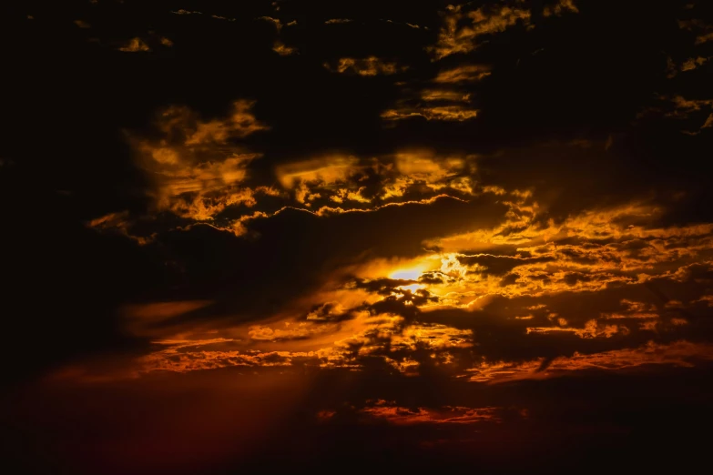 a cloud shaped orange sun rises in the dark sky