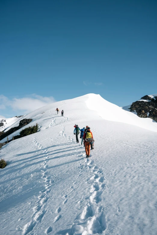 four people walking down a large snowy hill