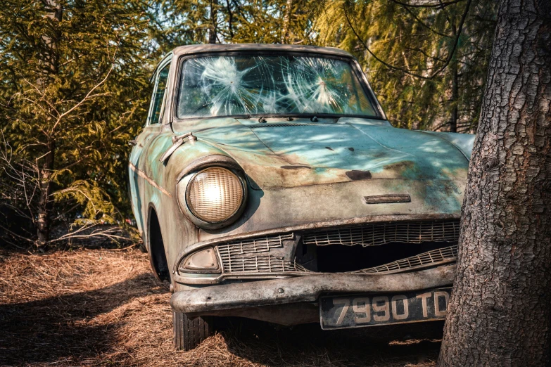 an old car that is parked next to a tree