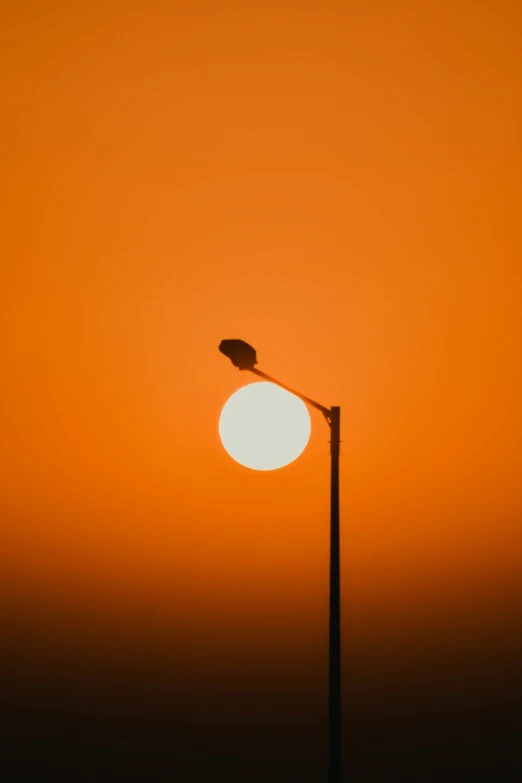 street light with sun in background, against the sky