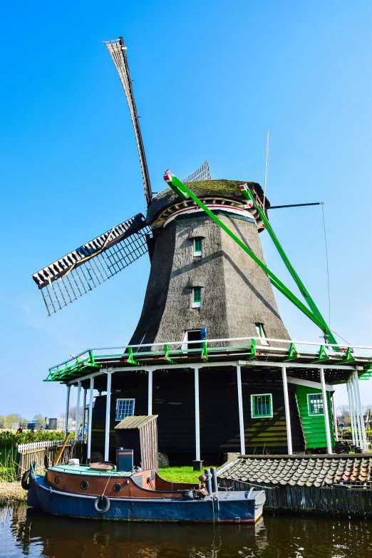 a boat that is on the water in front of a windmill