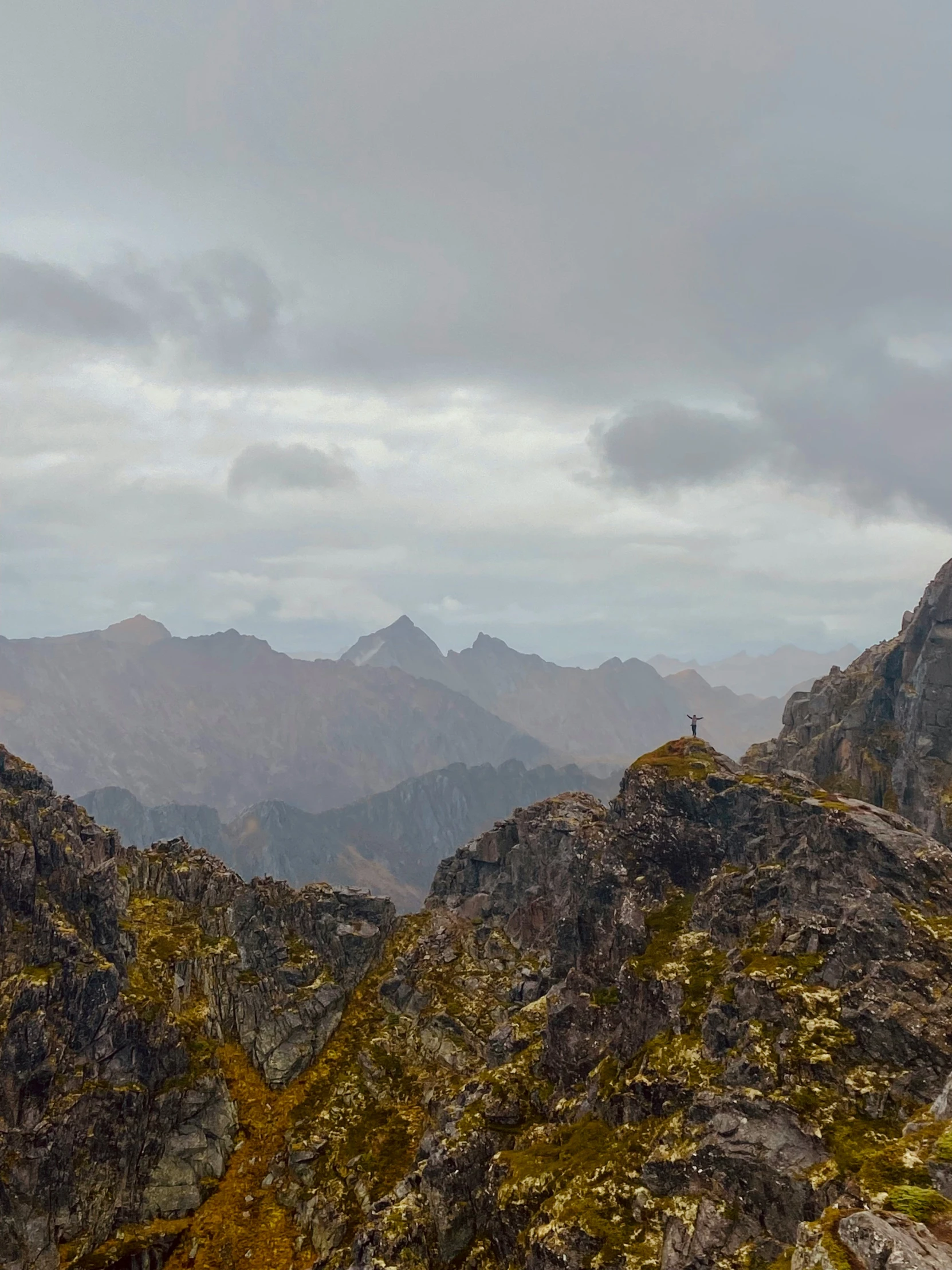 there is a lone person standing on a mountain peak