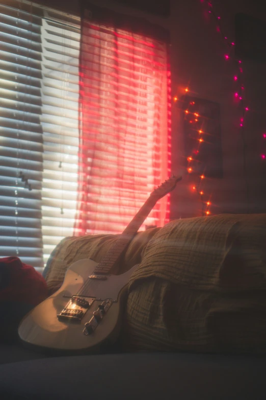 a guitar is laying against the couch by the window