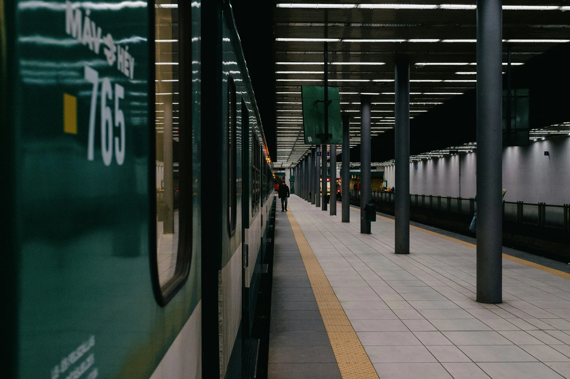 the empty train station has three green trains parked next to each other