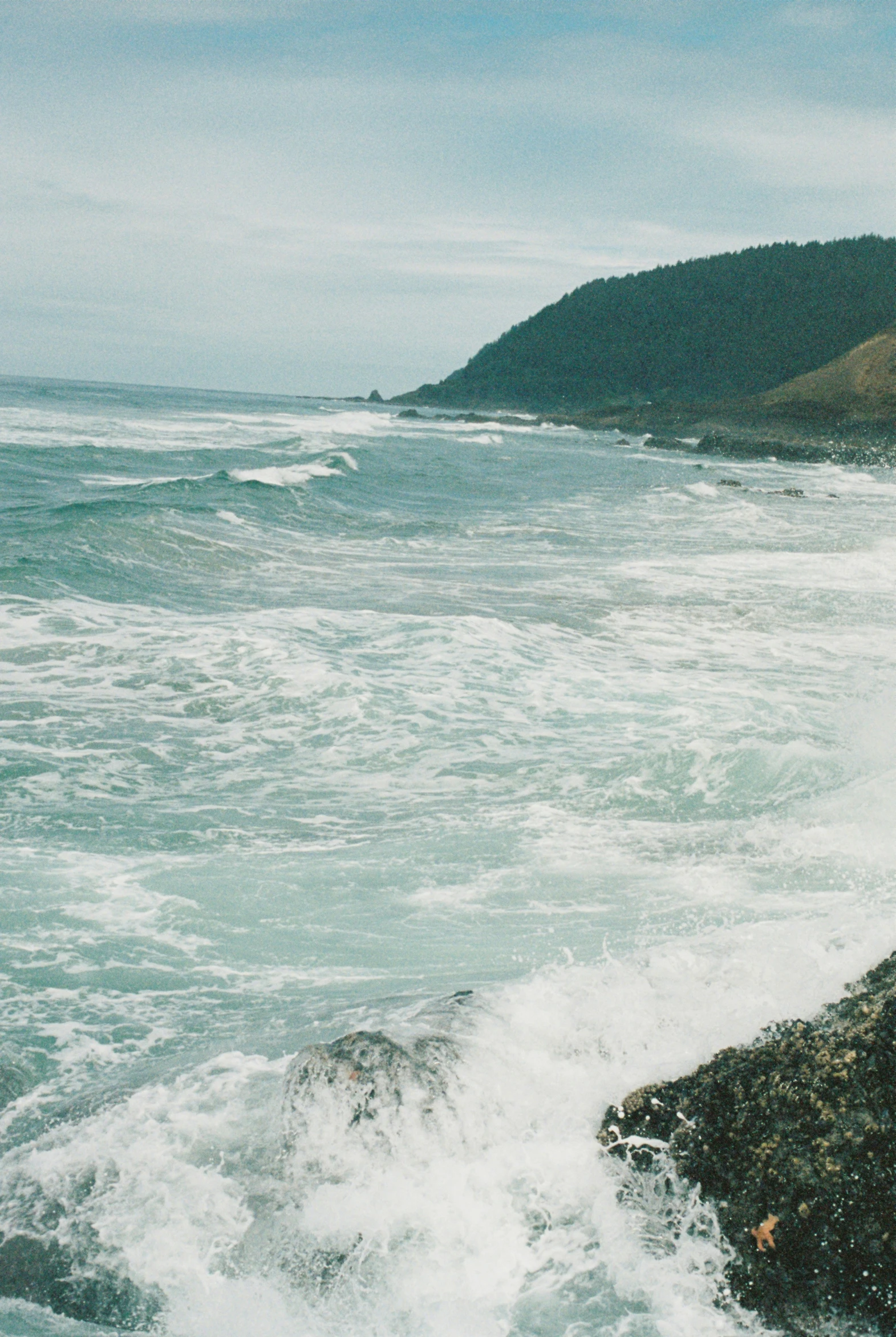 ocean waves crash on the rocks of an otherwise deserted shoreline