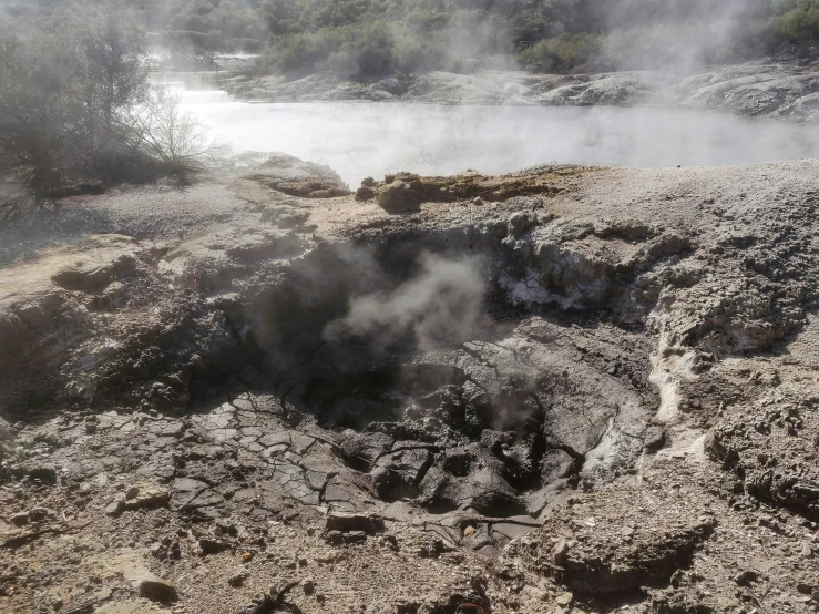 a small pond with steam is surrounded by rocks