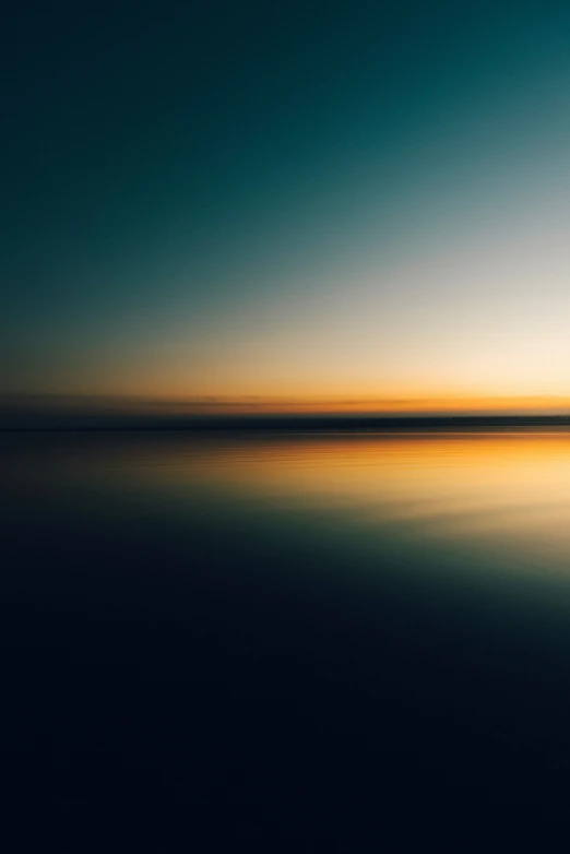 the sun sets over water as it is reflecting the sky