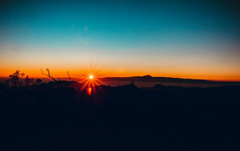 a very bright sun setting over the mountains