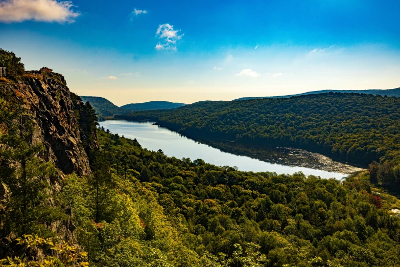 the view from atop a hill in a mountain valley with a river running between two sides of a cliff