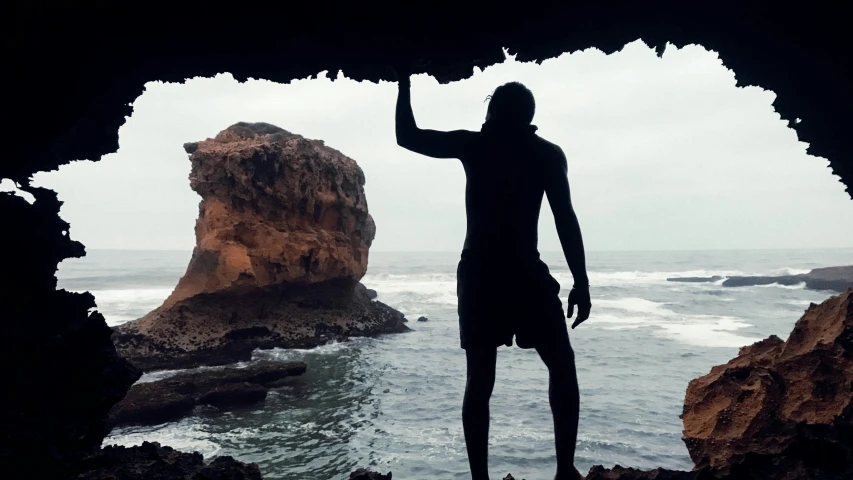 a person standing in a cave near the ocean