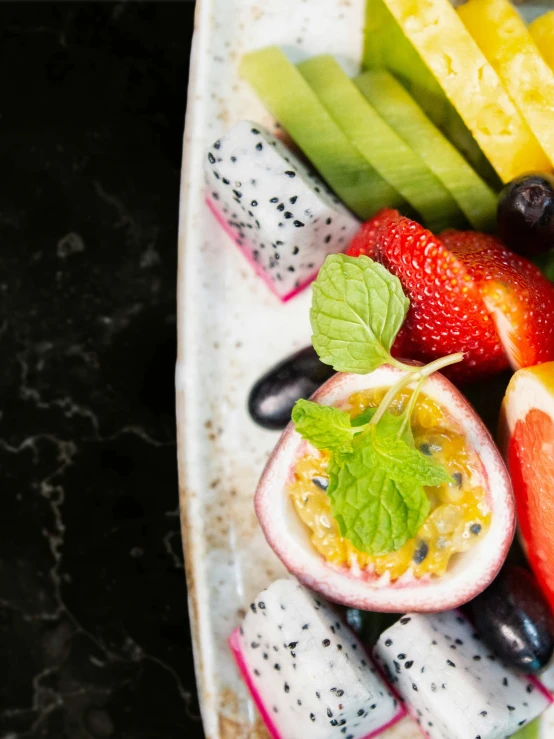 a plate of fruits and vegetables, including kiwi, bananas and strawberries