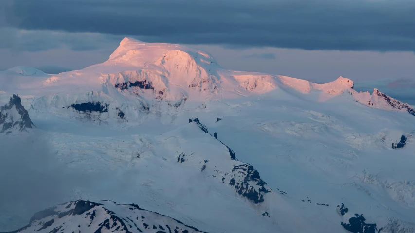 the top of a mountain with snow on it's peaks