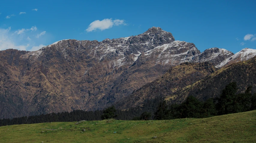 the mountain range has green grass on both sides and a sheep in the middle of it