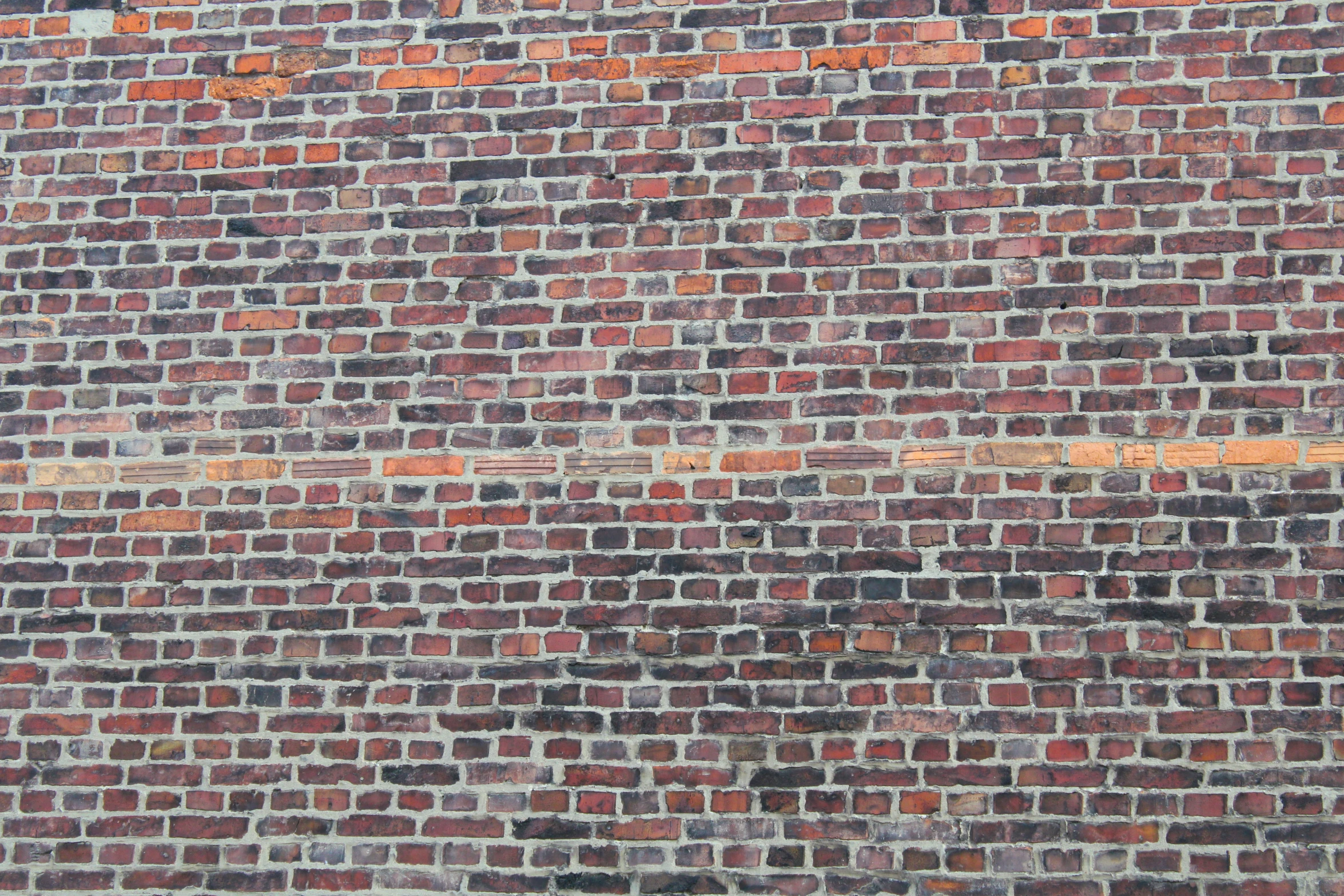 the wall of an old building has faded bricks and paint on it