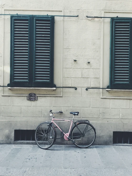 a pink bike parked outside of a building