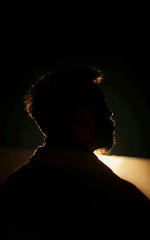 man facing back in dark room with headlight on