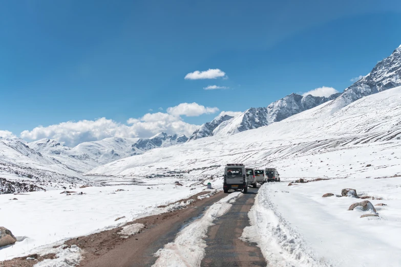 a truck driving down a snow covered road in the middle of mountains