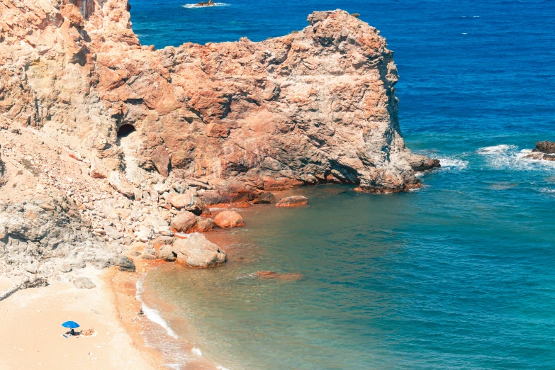 a sandy beach next to a cliff by the ocean