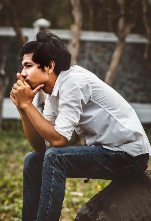 man sitting on a rock in a park