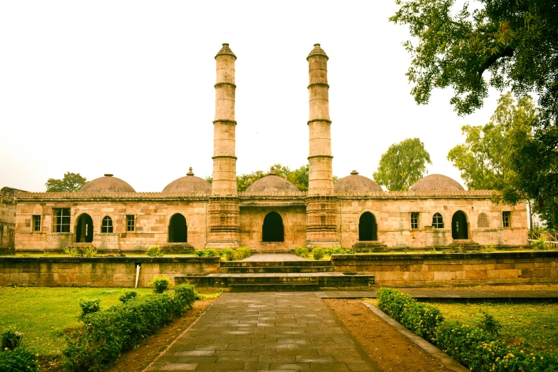 an old brick building with two towers and a stone path