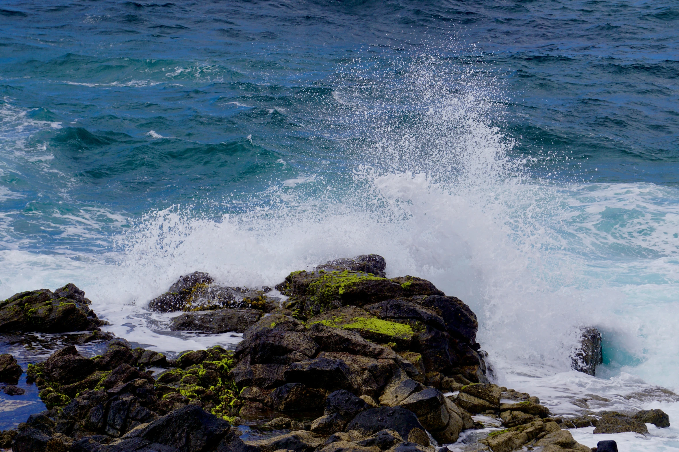 the ocean crashing into a rock with a spray of water coming off it