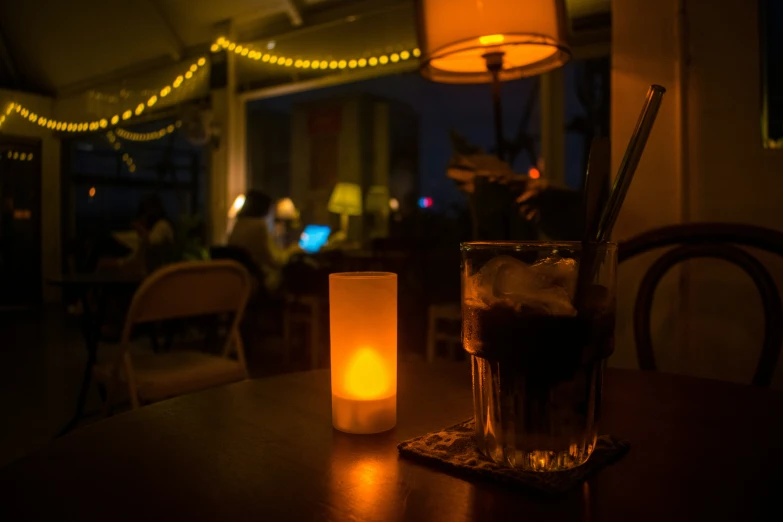 a table with a candle, glass and beverage sitting on it