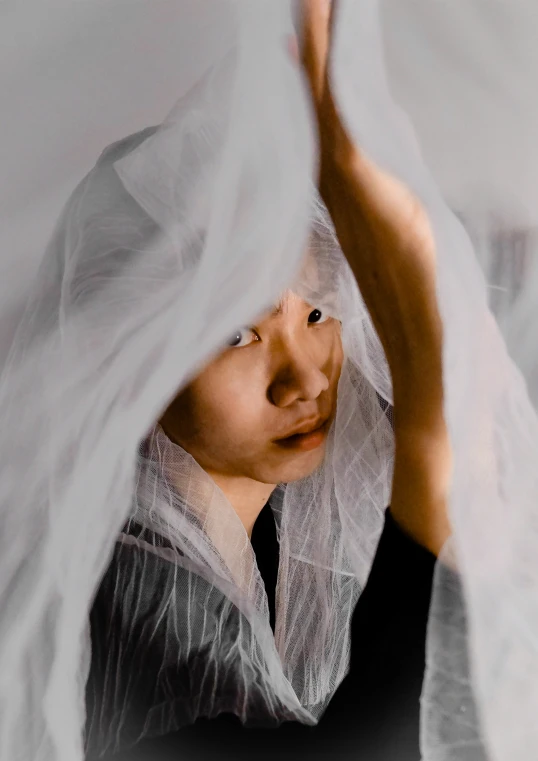 a little girl in an old fashioned costume is looking into the distance with a veil around her neck